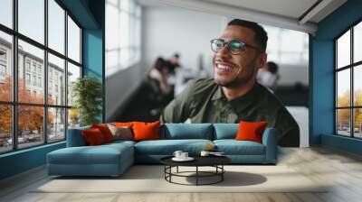 Portrait of a handsome casual businessman wearing black eyeglasses in office smiling Wall mural