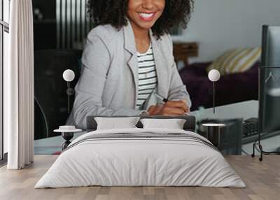 Portrait of a smiling professional businesswoman with diary and pen sitting in front of computer at her desk in an office looking at camera Wall mural