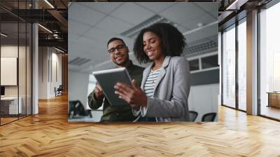 Portrait of smiling professional young African American businesswoman showing data on digital tablet to male colleague in office Wall mural