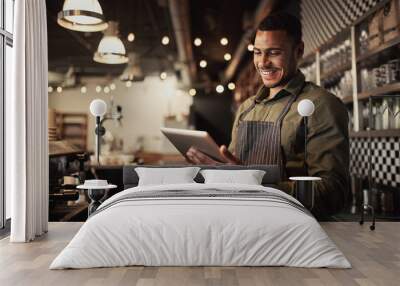 Portrait of successful young afro-american cafe owner standing behind counter using digital tablet Wall mural