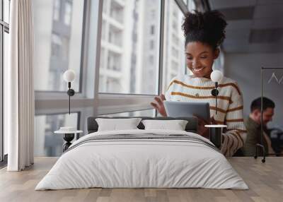 Smiling Brazilian female executive using a digital tablet in a modern architectural setting set in South America Wall mural