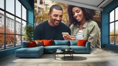 Smiling young couple looking at smartphone Wall mural