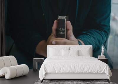 A Man praying holding a Holy Bible and praying in bed room. religion, praying, education and bible study. Christian concept.. Wall mural