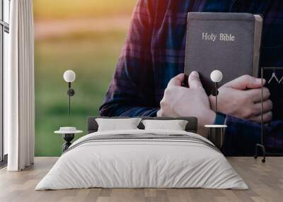 Man in hold and hugging holy bible on the bench. christian praying believe concept. Wall mural