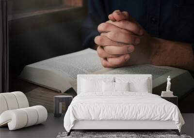 Man is reading and praying the scripture or holy bible on a wooden table with copy space. Religion, believe Concept. Wall mural