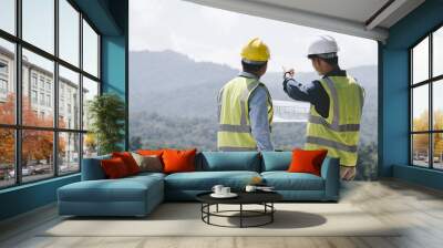 Two young maintenance engineer man working with blueprint on the mountain, Environmental engineering concept.. Wall mural