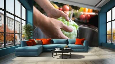 Young man washing vegetables for salad in the kitchen. Vegetables in the sink on kitchen. Fresh vegetables. Homemade Wall mural