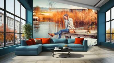 glamourous portrait of the young beautiful woman in leather boots on the bank of a lake on wooden pier Wall mural