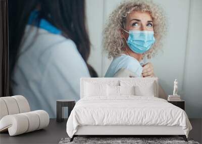 Caucasian curli woman in medical mask receiving vaccine injection with syringe in modern clinic. Looking scared. Coronavirus safety. Coronavirus vaccination Wall mural