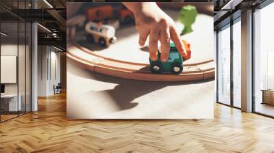 caucasian kid is playing with toy train on the railway on the floor Wall mural