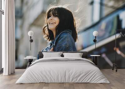 Close up portrait of a amazing short haired brunette dressed in blue jeans jacket looking away laughing outdoor. Wall mural