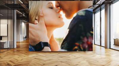 Close up portrait of a cute young caucasian blonde couple trying to kiss where man is holding his girlfriend face in his hands close outside while dating. Wall mural