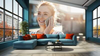 Close up portrait of a ginger lady with freckles posing outside with a laptop during a sunny day while talking on phone Wall mural