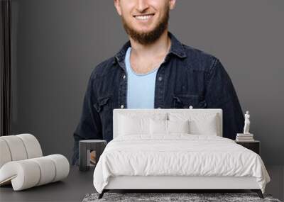 Ginger caucasian man with beard holding a tablet and promoting IT services while smiling on a gray studio wall Wall mural