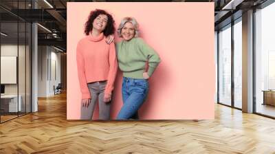 Monochrome photo of two women with curly hair posing on a studio wall with free space smiling at camera Wall mural