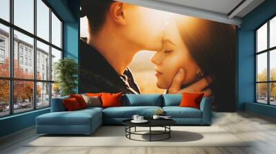 Side view of crop male kissing pretty girlfriend in forehead while spending time in nature on sunny day.Crop guy kissing girlfriend in forehead in nature Wall mural