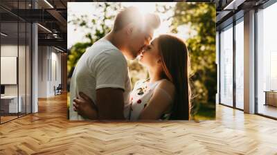 Side view portrait of a amazing caucasian couple kissing against golden hour light embracing while dating outside. Wall mural