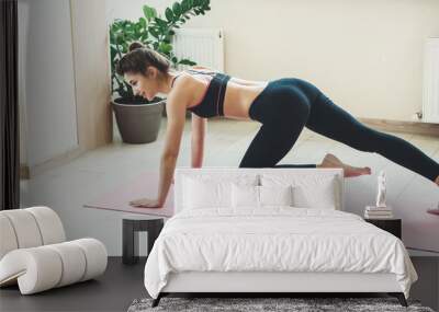 Sporty woman is planking at home using a laptop and smile wearing sportswear Wall mural