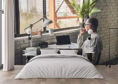 Thoughtful caucasian man is looking at the window working at the office with the tablet and photo camera Wall mural