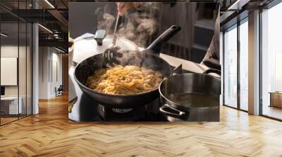 Professional chef cook making vegetarian Italian Tagliatelle pasta with mushrooms and cream at modern kitchen gas stove in wok pan. Wall mural