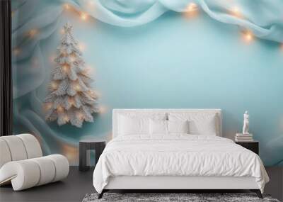 Small Christmas tree with lights and elegant blue scarf. Bright and creative flat lay with soft pastel blue background and big copy space. Wall mural