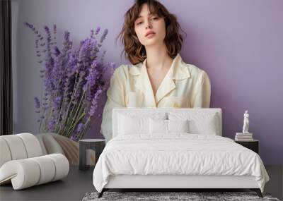 A fashion model presenting a casual chic ensemble, her natural elegance emphasized by the soft contours of the clothing, set against a pastel lavender background Wall mural