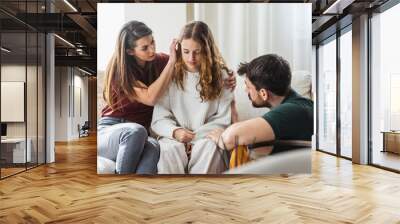 Parents comforting their young daughter. Wall mural