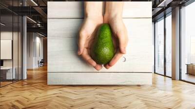 Ripe avocado in hand Wall mural