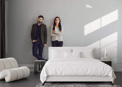 A businessman and a business woman are standing against a gray wall Wall mural