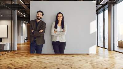 A businessman and a business woman are standing against a gray wall Wall mural