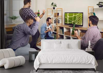 A group of young comrades watch a football game at home on TV, celebrating a goal-scoring beer and pizza. Happy friends watching soccer match, hanging out together concept Wall mural