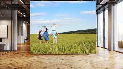 a happy family is walking in a wheat field in the summer. back view. Wall mural