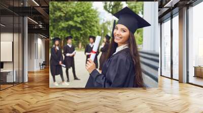 A young female graduate against the background of university graduates. Wall mural