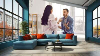 Annoyed young family couple arguing emotionally, blaming each other. Stressed irritated woman and man shouting at each other having serious relations communication problems. Couple quarreling at home Wall mural