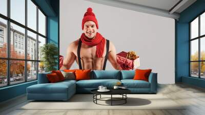 Athletic man with gifts smiling at christmas. Wall mural