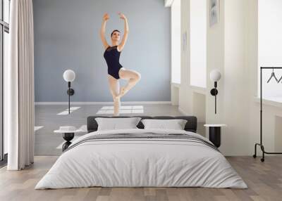 Ballerina. Young graceful ballet dancer is rehearsing a performance in a white studio with windows. Wall mural