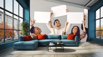 Banner with group of five happy smiling diverse people, colleagues or friends, expressing opinion and giving positive feedback holding white mockup signs and sheets of paper on gray studio background Wall mural