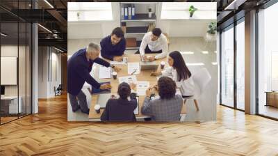 Brainstorming in a modern office. Serious business team analyzes sales charts and diagrams, develops a new strategy and discusses work issues. Concept of teamwork on the project. Top view. Wall mural