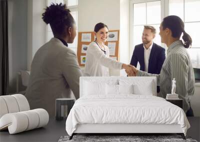 Business handshake. Happy young people greeting each other in group meeting. Smiling manager shaking hands with client after successful negotiation at the company office Wall mural