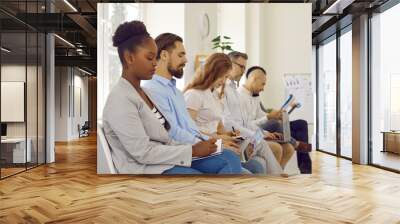 Business people who are studying and increasing their level of professionalism attend business training. Serious and focused multiracial people sitting in row on chairs and writing down information. Wall mural