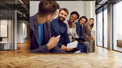 Business team meeting in the office, working together, making presentations, and having discussions. Group of happy multiracial men and women sitting in a row and discussing each other's ideas Wall mural