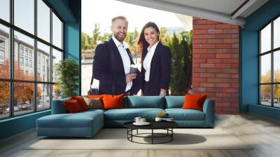 Businessman and business woman standing smiling outdoors. Wall mural