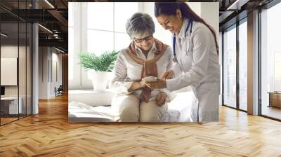 Caring doctor teaches female patient to use mobile healthcare app. Retired lady sitting in hospital exam room looking at cell screen learning to download health tracker for senior citizens. Copy space Wall mural