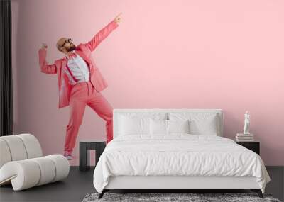 Cheerful successful man dancing funny making movements winner isolated on pink background. Funny man in pink formal suit celebrates his success having fun at copy space. Full length. Banner. Wall mural