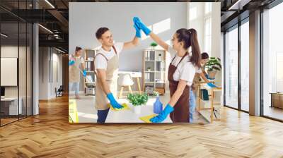 Cleaner happy group high five, working, professional janitor service busy completing cleaning tasks at home, office. Young people employed to take care of room, small company maintaining washing  Wall mural