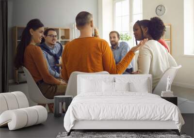 Close-up rear view on discussion. Group therapy session. Diverse multiethnic people sitting in circle and talking. Young caucasian man sharing problem to receive help and support from team Wall mural