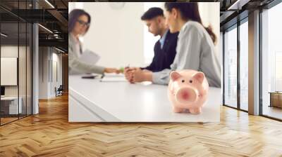 Closeup of pink piggy bank in credit advisor, loan broker or bank manager's office, couple signing document in copyspace background. People, money, opening account, family finance consulting concept Wall mural