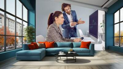 Colleagues analyze financial balance of company together, working with diagram on computer screen. Male and female financial analyst in office calculate financial data for long term investment. Wall mural