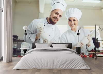 Confectioners with a bag for the cream will decorate the cake. Wall mural