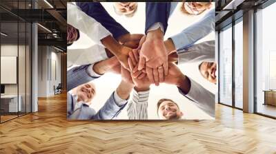 Diverse business team standing together and stacking hands. Happy senior and young mixed race multiethnic people pile up their hands and smile. Bottom view, shot from below. Teamwork concept Wall mural